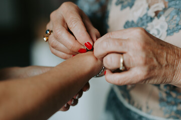 Grandmother putting on bracelet of granddaughter