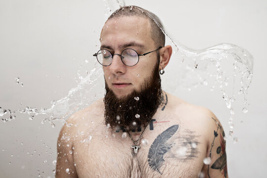 Bearded man in glasses under splash of water