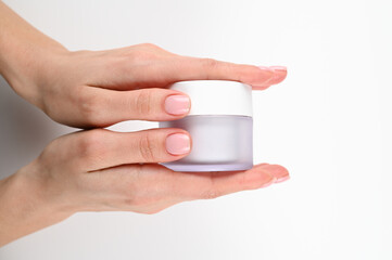 Female hands hold a jar of cream, on an isolated background