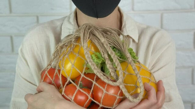 Packet with eco food. A woman in a protective mask hugs an eco string bag.