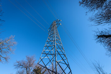 Photography of a High voltage tower, power line with electric cables and insulators against a clear...