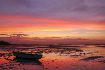 Colorful sunset with outrigger fishing boat on Walakiri beach near Waingapu on Sumba island, East Nusa Tenggara, Indonesia