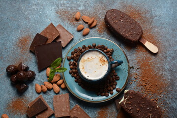 Cup of coffee, chocolate flavor popsicle, almonds, coffee beans, and tasty chocolate pieces .