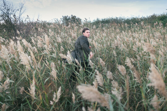 Young man running in sunset fall reeds.