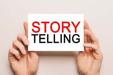 Female hands hold card paper with text Storytelling is the best marketing on a yellow background. Business and finance concept