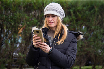 adult woman in coat using mobile phone