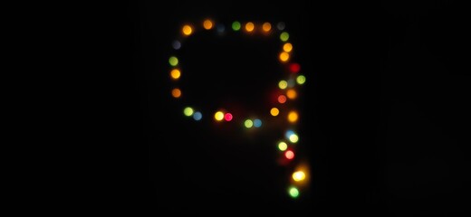 Closeup of Number nine, (9) made with multicolored blurred bokeh Christmas lights in a isolated black background with copy space
