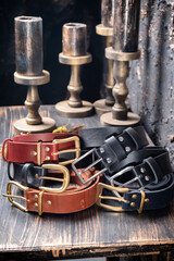 Fototapeta premium Six leather multi-coloured straps lie on a wooden table against a backdrop of vintage candles.