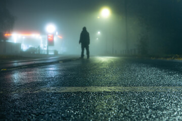 A low angle, shallow depth of field, of a hooded figure standing in the road
