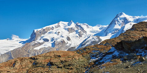 Panoramic view of the high snowy mountain peaks near Zermatt village in Switzerland in the autumn season.