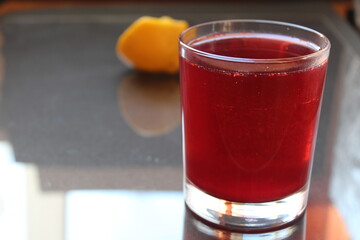 Berry red homemade juice juice compote morse strawberry raspberry on a black grey dark background with a ist for text and a copy of the lemon on the back pan view from the side © Кристина Шоба