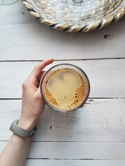 a female hand in a fitness bracelet holds a mug of coffee on a background of white boards