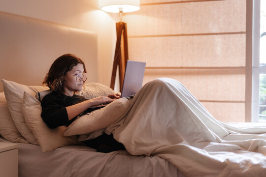 millennial woman working at home on the bed