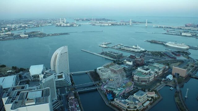 YOKOHAMA, JAPAN : Aerial sunset cityscape of “Minatomirai area“. Seaside urban area in central Yokohama city. View of buildings around the harbor or port or bay. Time lapse zoom in shot dusk to night.