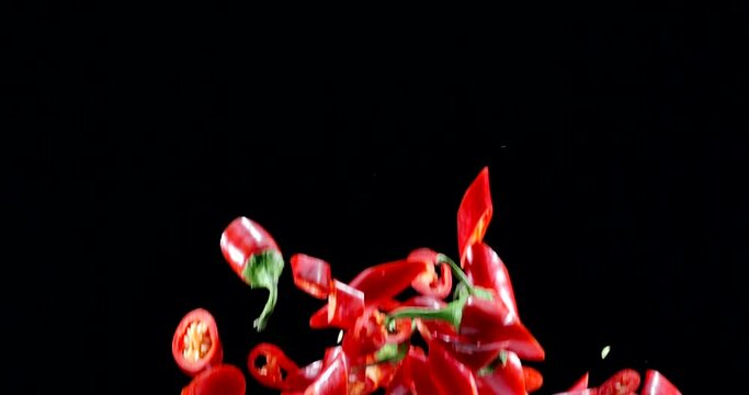 Red chili peppers slowly fly up and fall on a black background. Blackmagic Ursa Pro G2, 300 fps.