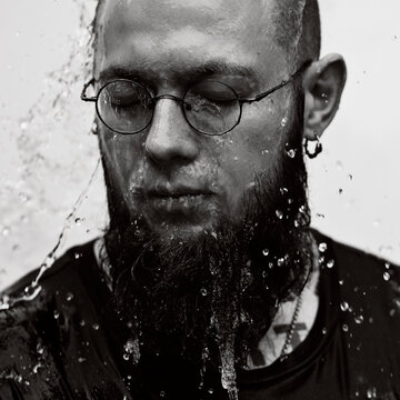Young man with tattoos under a stream of water