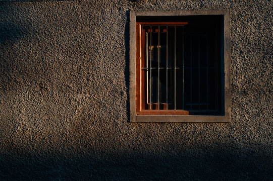 Window with metal bars lit by sunset