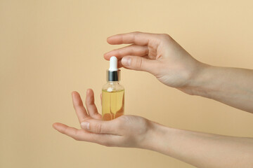 Female hands hold bottle with pine oil on beige background