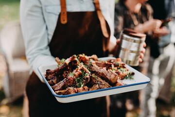 Waiter with leather apron serving meat
