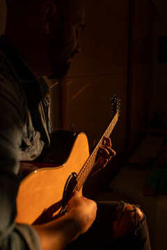 Young man playing acoustic guitar at home
