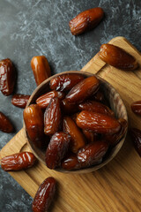 Board with bowl of dried dates on black smokey background