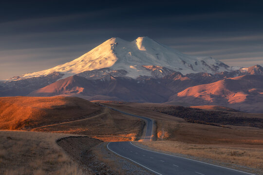 Mountain in sunrise color with hills in the foreground.