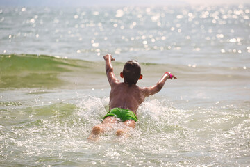 Fototapeta premium child swims in the sea waves on the beach