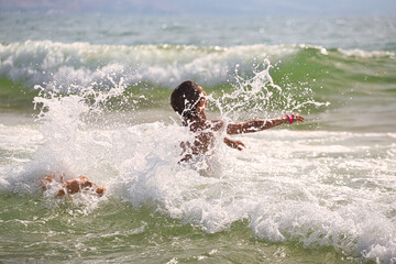 child swims in the sea waves on the beach - 420698301