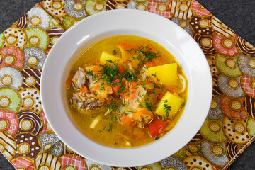 Meat soup with noodles and vegetables in a plate. Asian soup bowl on the dining table.