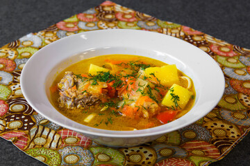 Meat soup with noodles and vegetables in a plate. Asian soup bowl on the dining table.