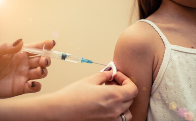 Little girl in the doctor's office is vaccinated. Syringe with vaccine against covid-19 coronavirus, flu, infectious diseases. Injection after clinical trials for human, child. Medicine concept.