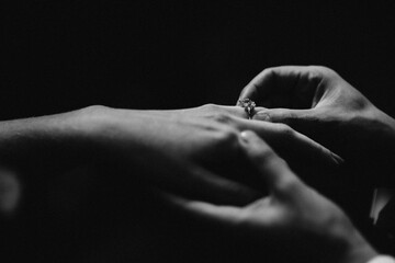 monochrome image of putting ring on woman
