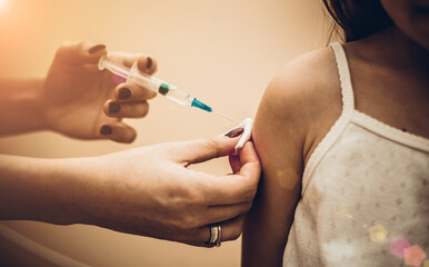Little girl in the doctor's office is vaccinated. Syringe with vaccine against covid-19 coronavirus, flu, infectious diseases. Injection after clinical trials for human, child. Medicine concept.