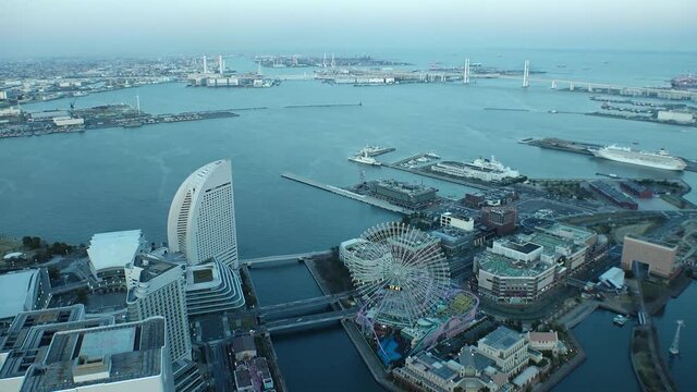 YOKOHAMA, JAPAN : Aerial sunset cityscape of “Minatomirai area“. Seaside urban area in central Yokohama city. View of buildings around the harbor or port or bay. Time lapse zoom out shot dusk to night