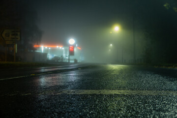 A low angle shot of a road and petrol station street on a foggy night
