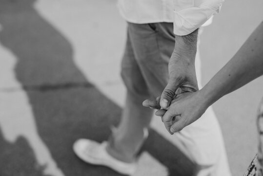 monochrome close up of young couple walking holding hands