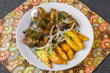 Fried meat with potatoes and vegetables. Hot food on a served platter.