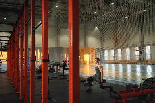 Sportsman building up muscles with dumbbells
