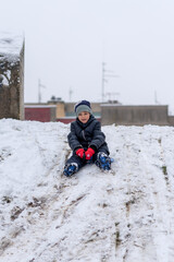 Fototapeta na wymiar Boy On A Plastic Sled Playing on The Snow