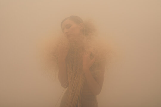 Woman with dry plants in fog