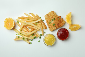Fried fish and chips, sauces and lemon on white background