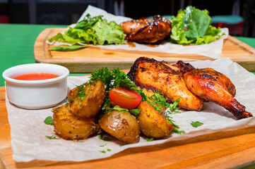 Juicy BBQ chicken leg quarters with fried potato. Food to go