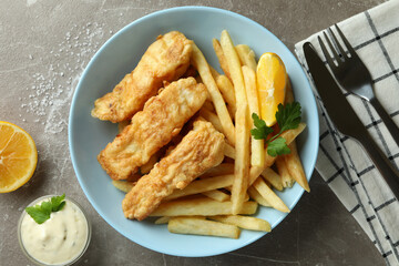 Concept of tasty eating with fried fish and chips on gray textured table