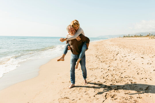 Happy couple piggyback at the beach