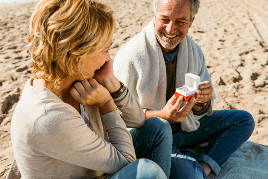 Mature couple propose at the fall beach morning