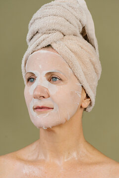 Peaceful woman with sheet facial mask in studio