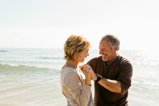 mature couple dancing and hugging at the beach