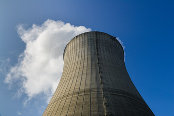 Contre-plongée d'une tour d'une centrale nucléaire d'où sort de la vapeur d'eau en fumée...