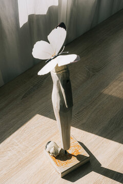 Broken sculpture with butterflies instead of head and the head on the table