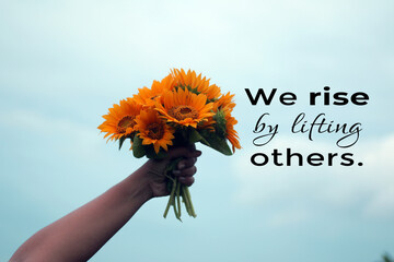 Inspirational quote - We rise by lifting others. Young woman showing bouquet of sun flowers in hand...